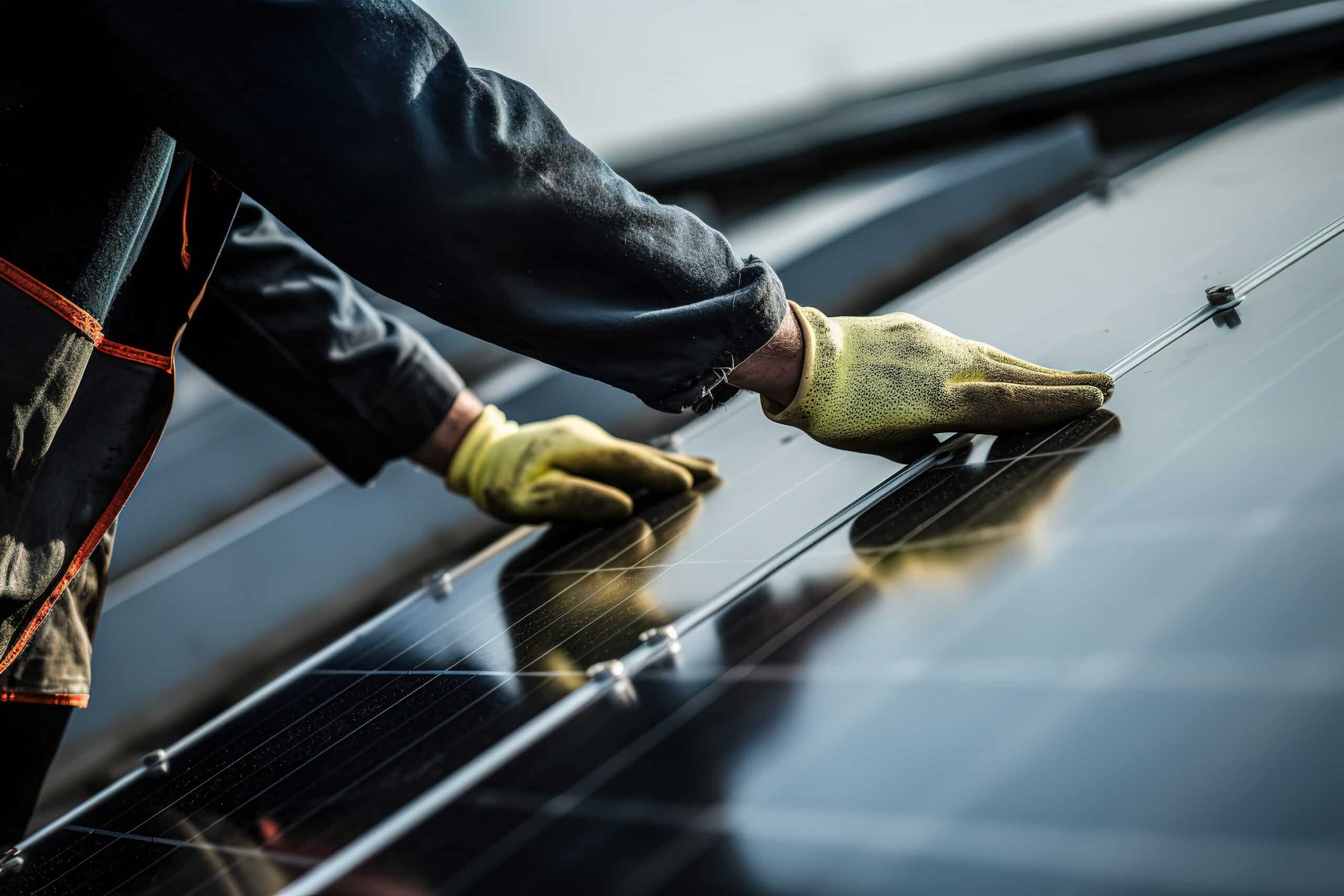 Gros plan sur un technicien en gants jaunes installant ou ajustant des panneaux solaires. Travailleur de l'énergie renouvelable.