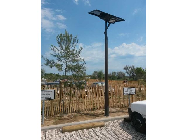 Éclairage solaire LED en zone de parking près de la plage. Panneau "Stationnement réservé" et "INTERDIT SAUF M.N.S. ET MOYENS DE SECOURS".